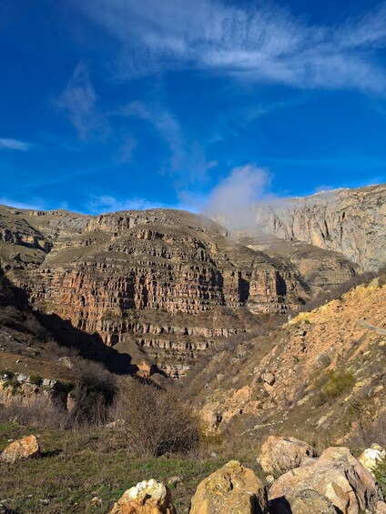Un paysage montagneux accidenté, avec des formations rocheuses en strates et un ciel bleu limpide. 4