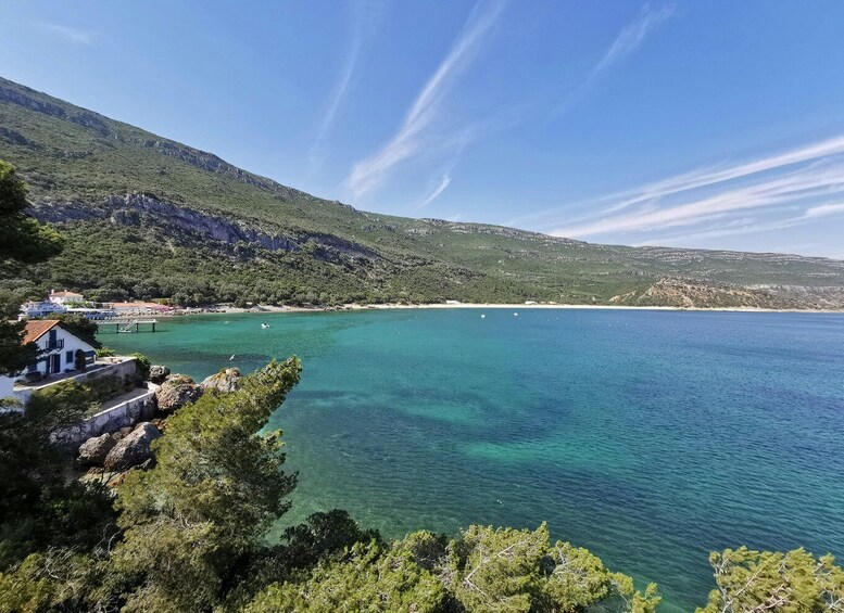 A coastal landscape with clear turquoise waters, a small pier, and a hillside with sparse vegetation. 1