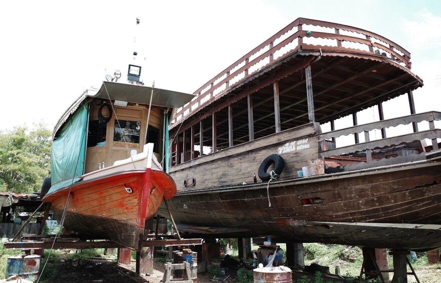 Two wooden boats, one red and one brown, on land. 4