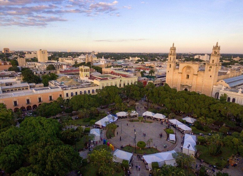 A cityscape with historic architecture, including a prominent church with twin towers, surrounded by a plaza with trees and market stalls. 5