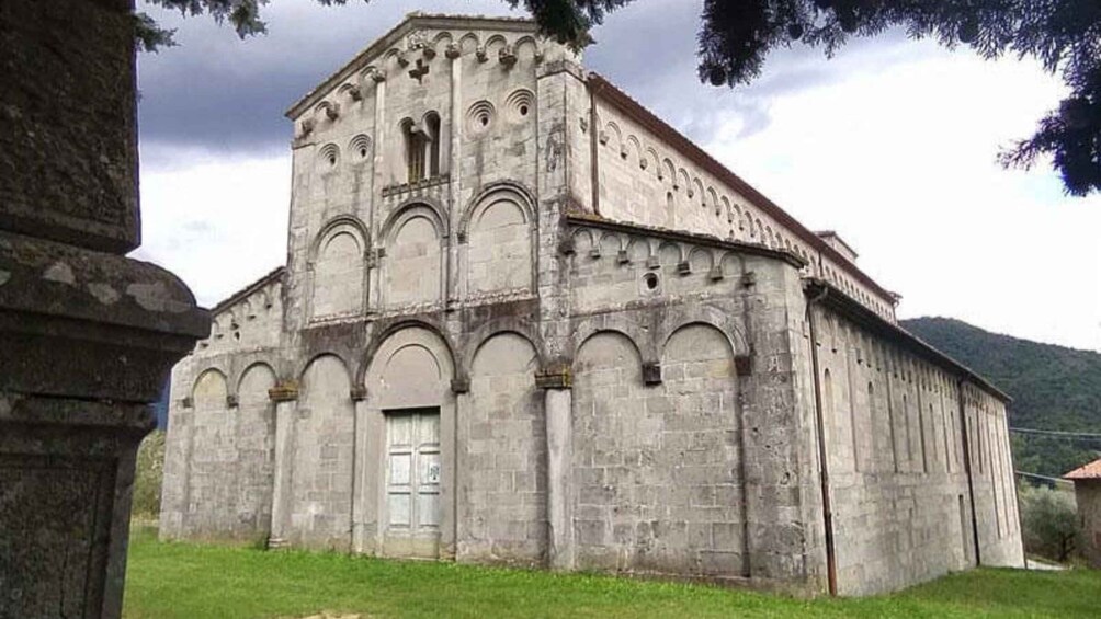 A large, historic stone church with a bell tower, arched windows, and a central door. 2