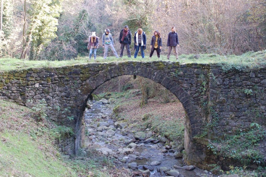 A stone bridge over a stream with people standing on it. 5