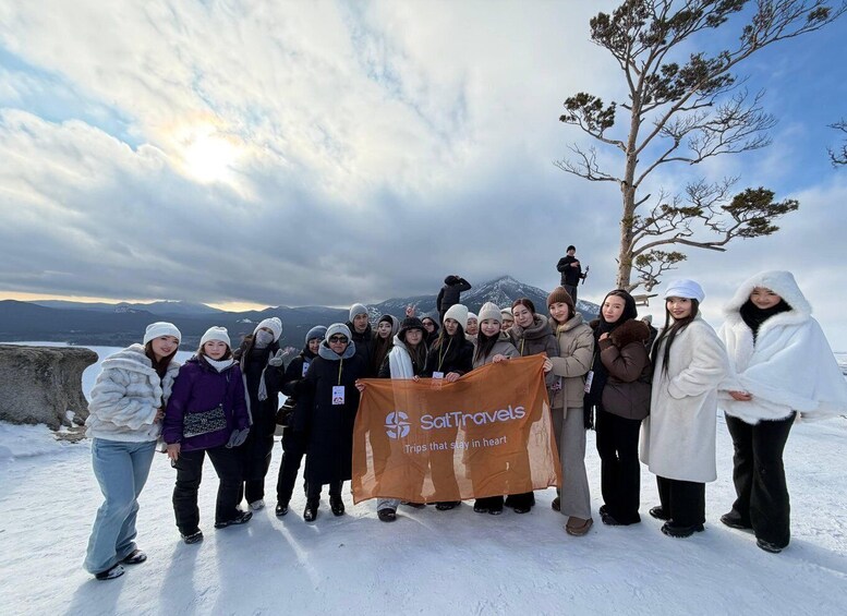 A group of people standing on a snowy mountain with a banner that reads 'SatTravels Trips that stay in heart.' 1