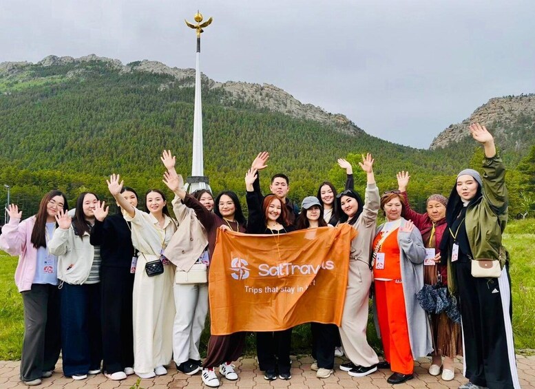A group of people holding a banner with a logo, standing in front of a mountain landscape. 5