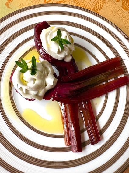 A plate with two beetroot slices topped with whipped cream and a sprig of herb, accompanied by a drizzle of oil. 1