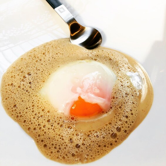 A close-up of a hot beverage with a spoon, frothy surface, and a clear liquid. 3