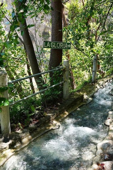 A signpost with 'LA GLORIA' and a stream flowing over rocks. 2