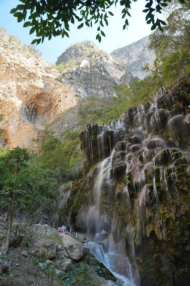 A waterfall cascading down a rocky cliff surrounded by greenery. 4