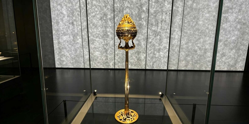 A golden artifact on a pedestal in a museum. 4