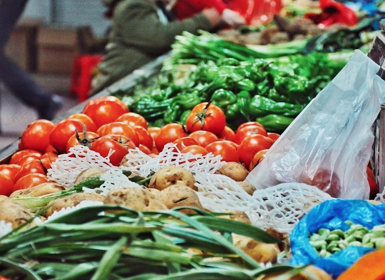 A market stall with tomatoes, green peppers, and other vegetables. 2