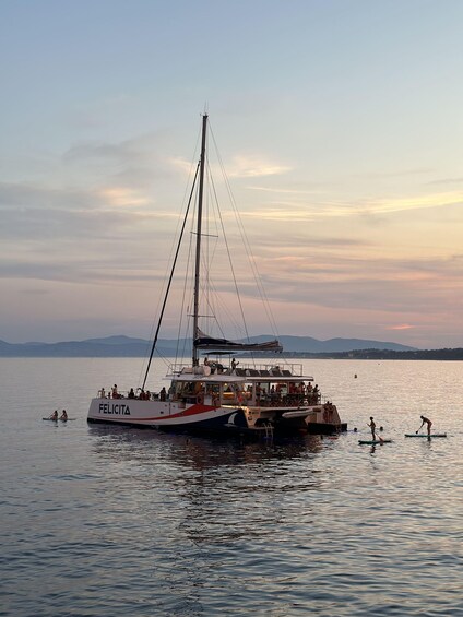 A sailboat named FELICITA with people on board and some on the water. 3