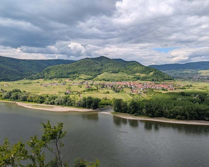 A river with a town on the opposite bank, surrounded by green hills. 2