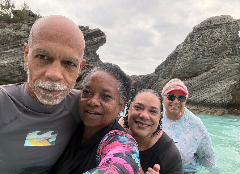 A group of people near rocky cliffs by a body of water. 2