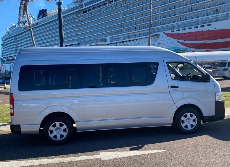 A white van parked on a road with a cruise ship and a red boat in the background. 5