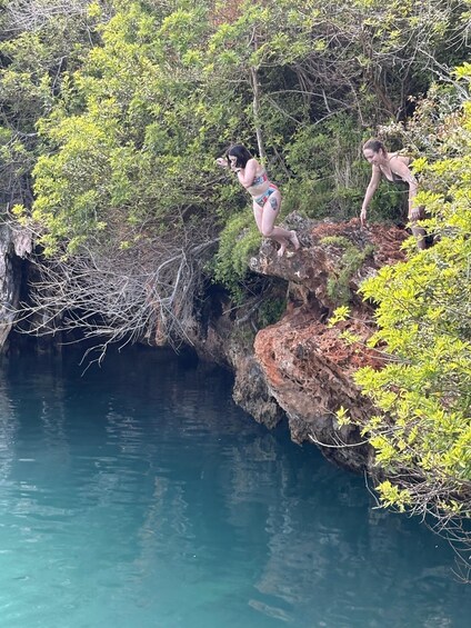 Two people on a rocky cliff overlooking a body of water. 1