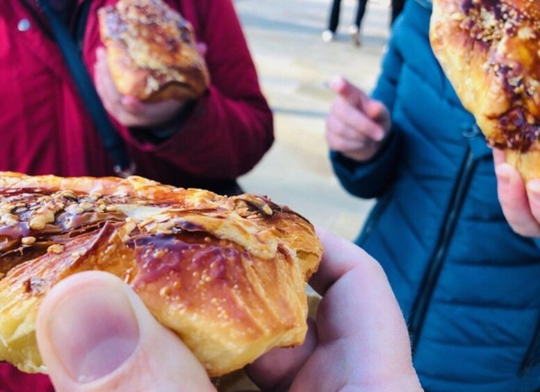 A person holding a pastry with visible nuts and a golden-brown crust. 1