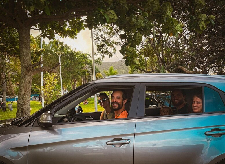 A blue car parked in a park with trees and a grassy area in the background. 5