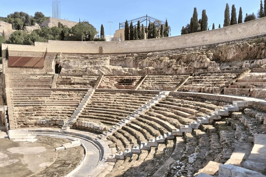 An ancient amphitheater with tiered seating and a central stage area. 2