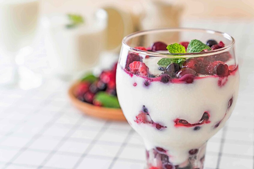 A glass of yogurt parfait with berries and mint. 1