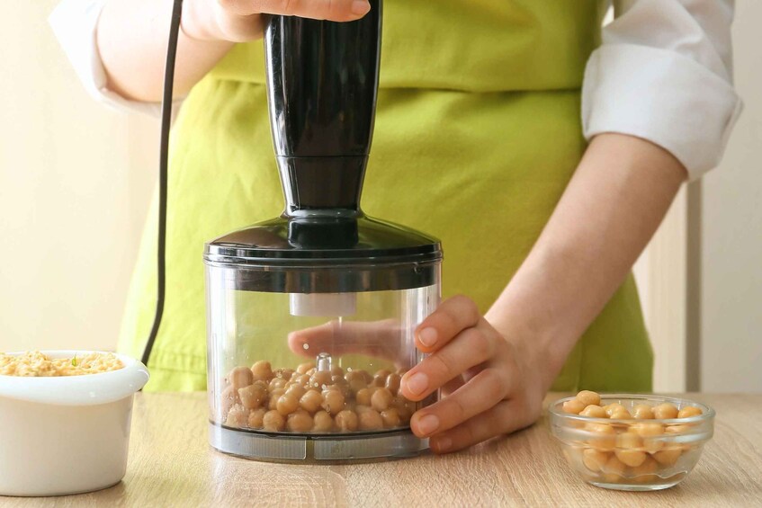 A person using a food processor to blend chickpeas. 4