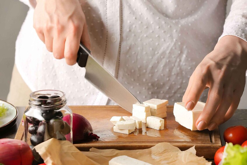 A person cutting cheese on a wooden board with a knife. 5