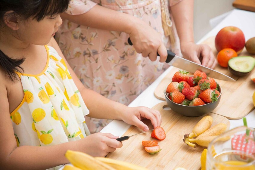 A person cutting strawberries on a wooden cutting board. 3