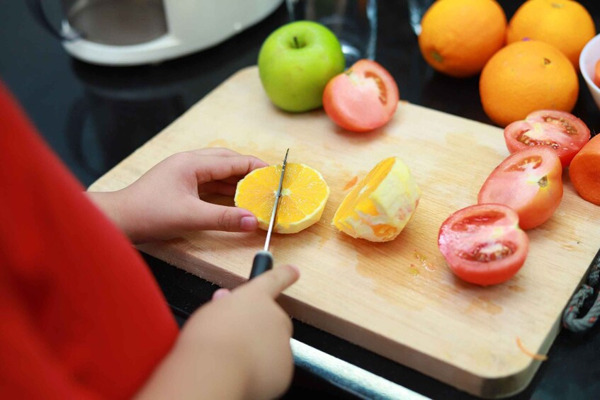 A person cutting an orange on a wooden cutting board with a knife. 5