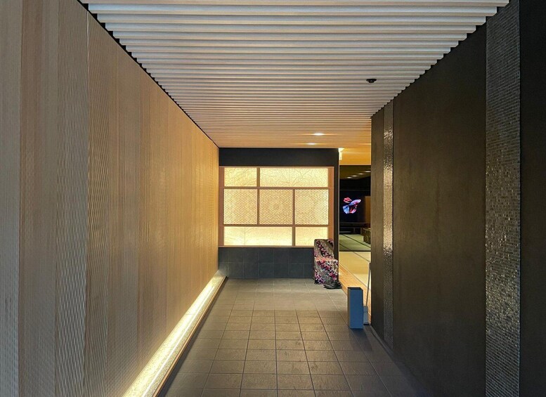 A corridor with wooden walls, a tiled floor, and a ceiling with horizontal slats. 5