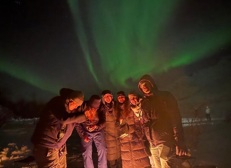 A group of people outdoors at night, with the aurora borealis visible in the sky. 5