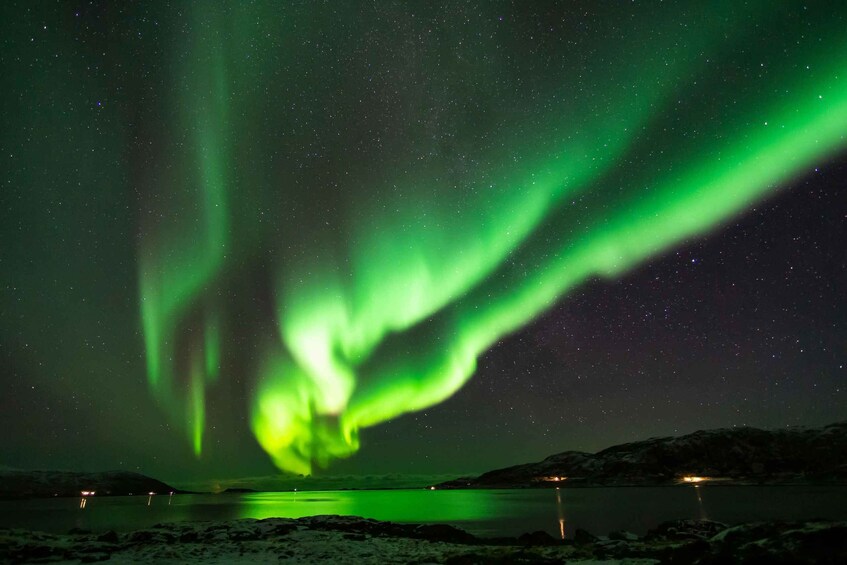 The Northern Lights over a calm lake with snow-covered hills. 3