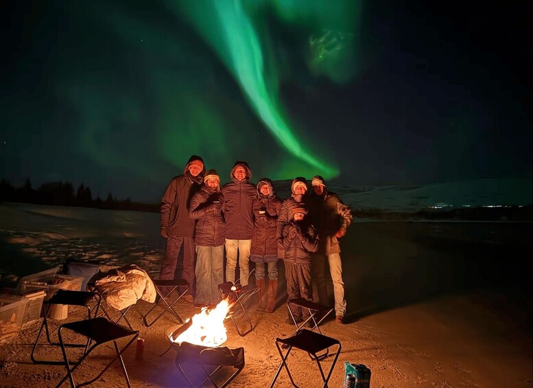 A group of people gathered around a campfire under the Northern Lights. 5