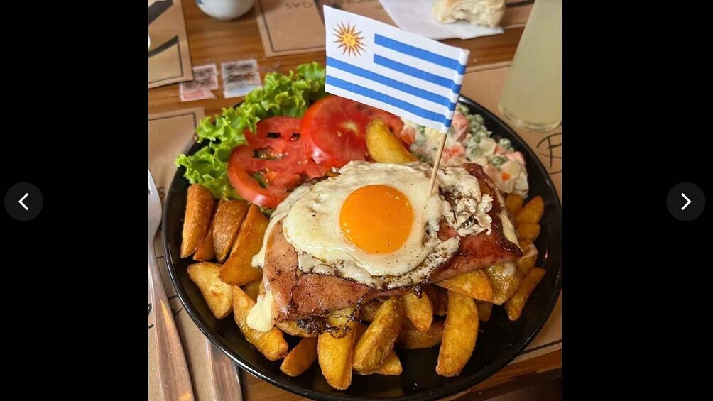 A plate of food with a fried egg, meat, fries, and a flag. 5