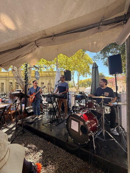 A band performing under a tent with musical instruments and a speaker. 2