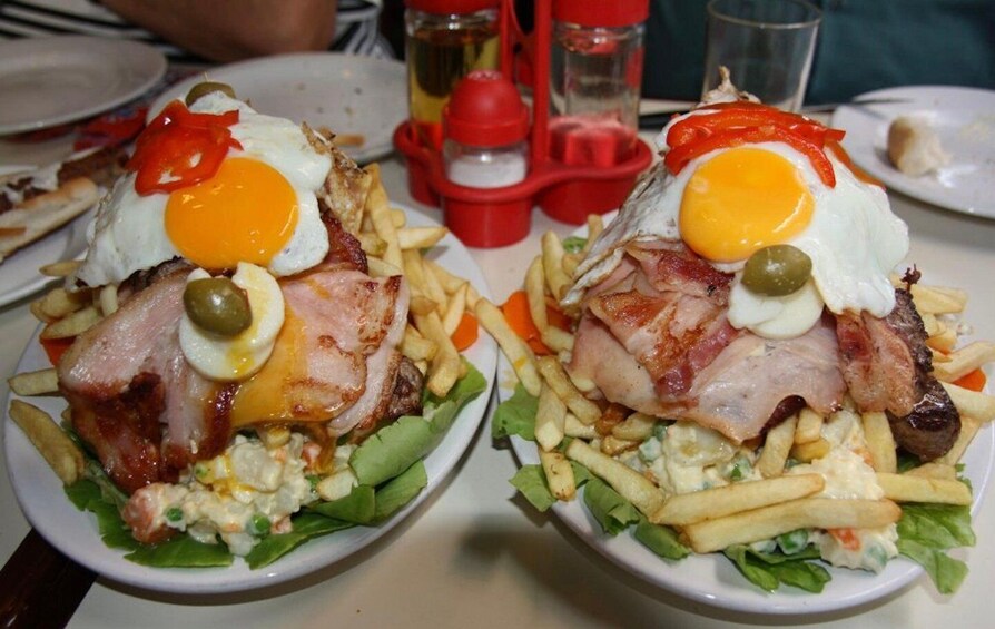 Two plates of food with eggs, bacon, and fries. 2