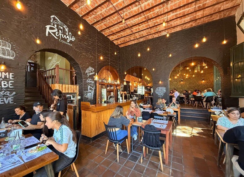 A restaurant with brick walls, wooden tables, and hanging light bulbs. 1
