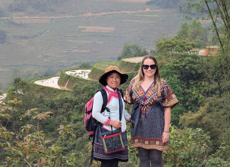 Two people standing on a hillside with terraced fields in the background. 3