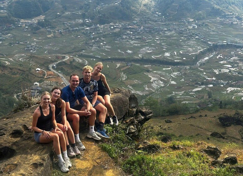 A group of people sitting on a rocky outcrop overlooking terraced fields. 2