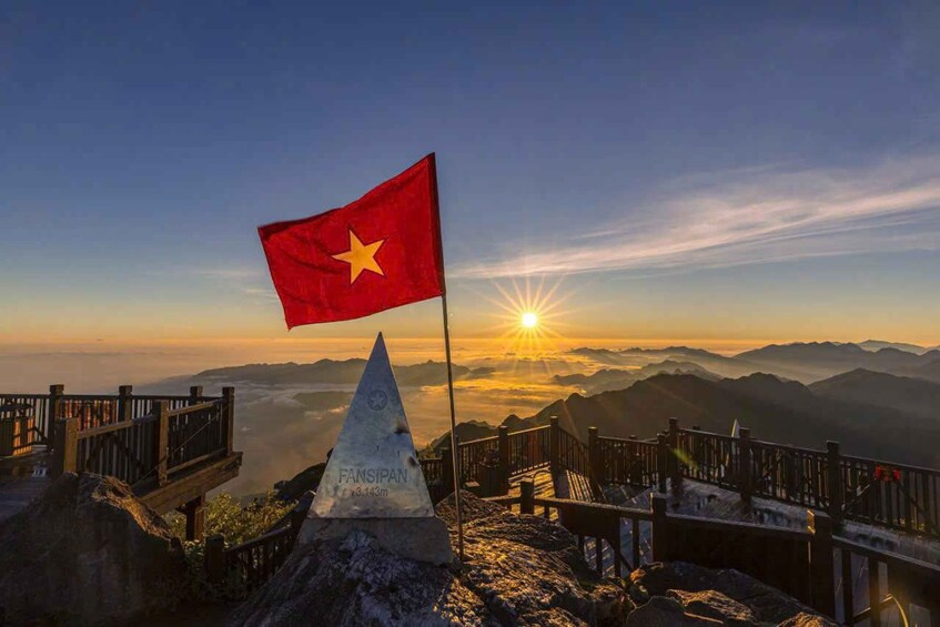 A flag on a mountain peak with a sunrise in the background. 1