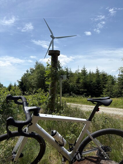 A mountain bike parked in a grassy area with a wind turbine in the background. 4