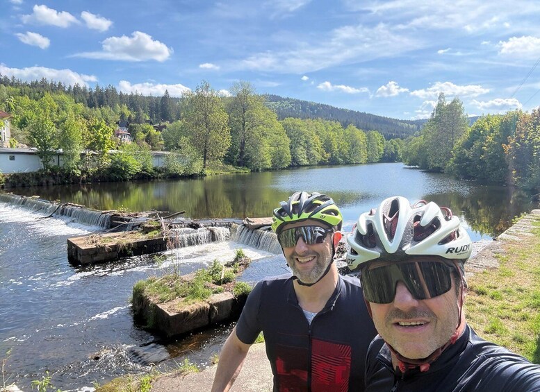Two people wearing cycling helmets near a waterfall and a river. 5