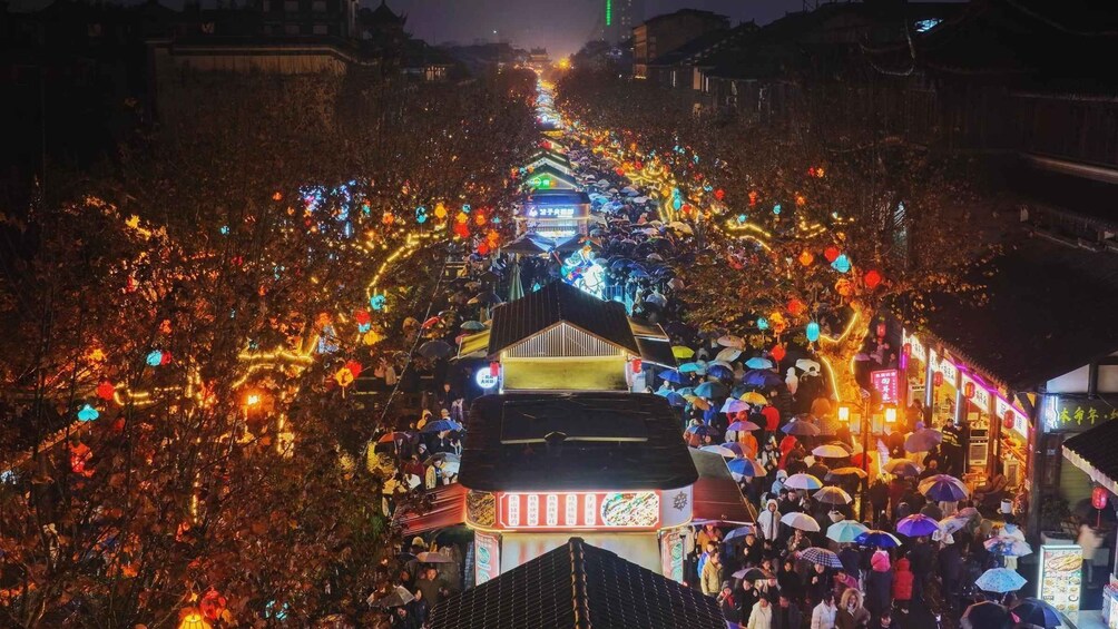 A bustling street at night with illuminated decorations and a crowd of people. 2
