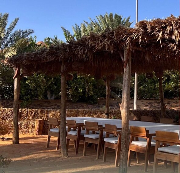 A thatched-roof outdoor dining area with wooden chairs and tables. 4