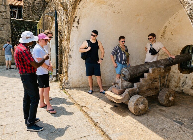 A group of people observing a large cannon in an outdoor setting. 3