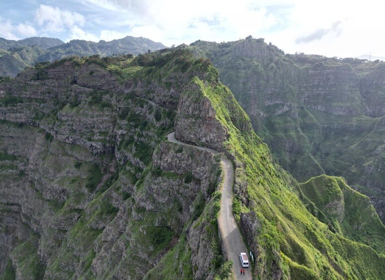 A winding mountain road with a vehicle and two people. 3