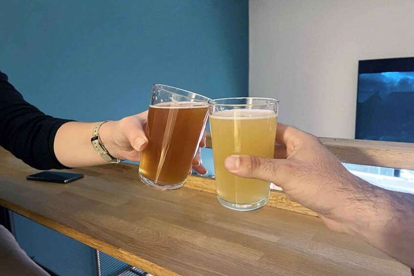 Two hands holding glasses of beer at a bar. 5