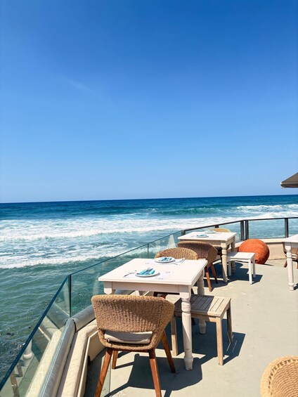 A seaside patio with tables and wicker chairs overlooking the ocean. 3