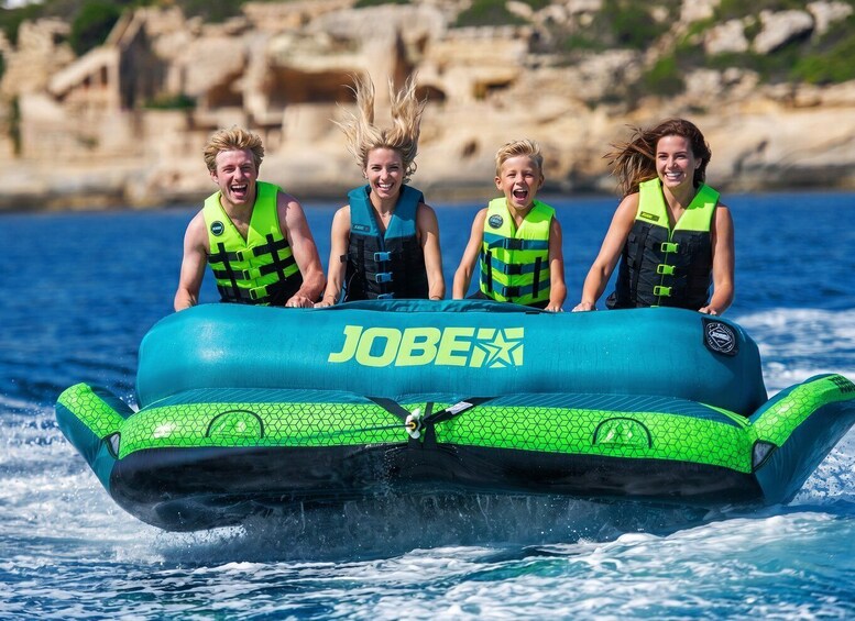A group of people on a blue and green inflatable raft with 'JOBEX' written on it, floating on water. 3