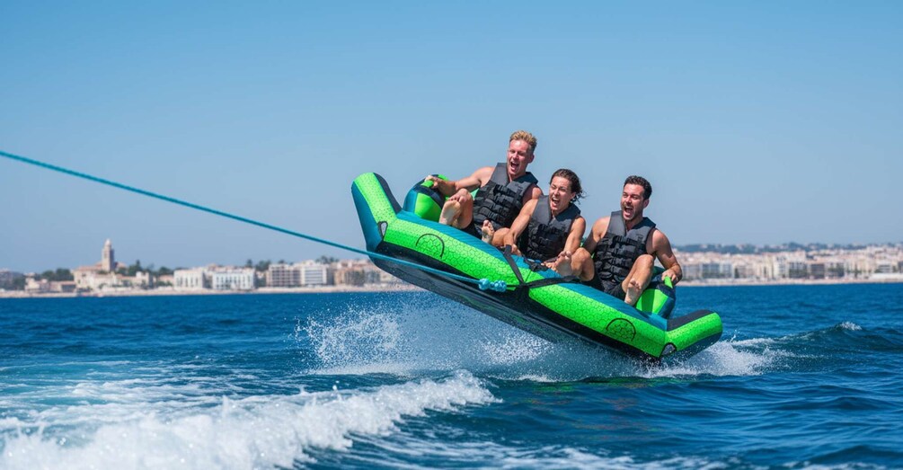 Three people on a green and blue jet ski in the water with a cityscape in the background. 1