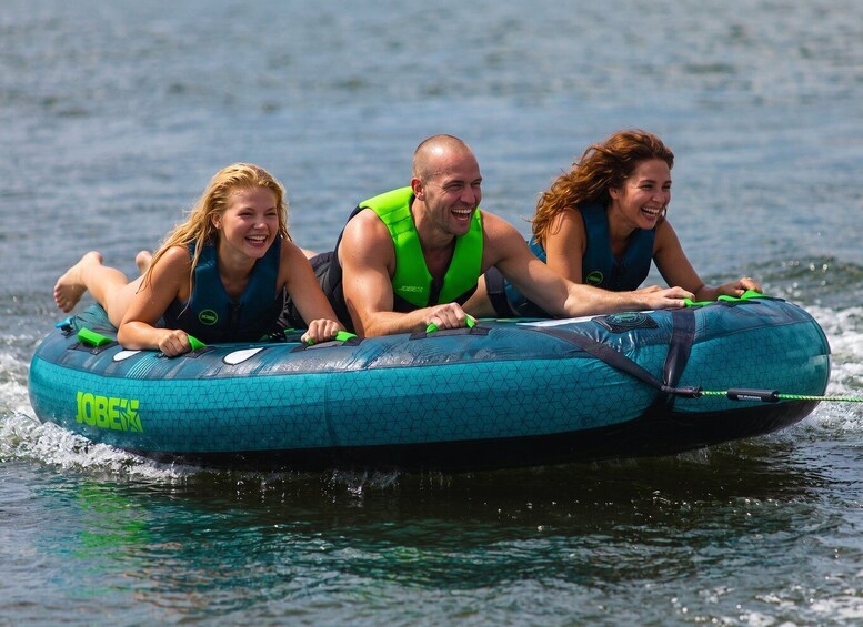 Three people on a blue inflatable raft with 'JOBEX' branding, floating on water. 2