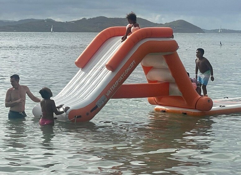 A large inflatable slide in the water with people interacting with it. 2
